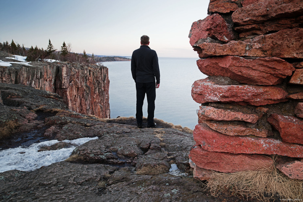 Man standing on the edge at Palisade Head - snow on rocks