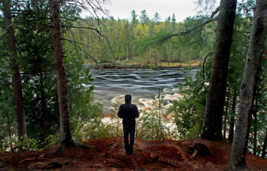 Man standing in the rain on cliffs above the Saint Louis River | Jay Cooke State Park