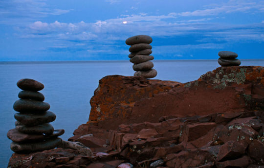 Rocks stacked on the beach with full moon in the background