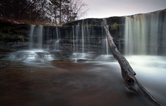 Log stripped of bark resting on Big Spring Falls | Big Spring Falls Banning State Park