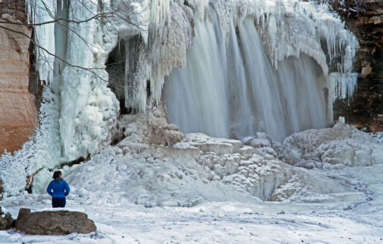 Girl standing on ice below frozen Minneopa Falls on New Year's Day | Minneopa State Park