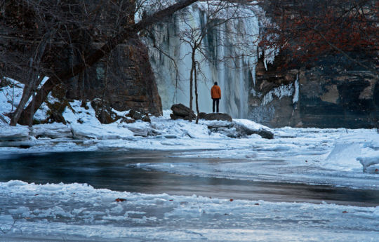 Man standing on the rocks below Minneopa Falls in winter | Minneopa State Park